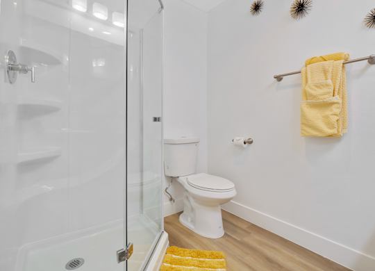 A white toilet sits in a bathroom next to a glass shower stall at Verandas Apartments, West Covina, 91791
