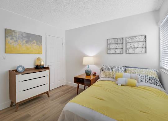 A bedroom with a bed, nightstand, and lamp at Verandas Apartments, West Covina, 91791