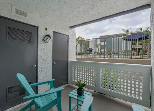 A balcony with a white railing and a black door at Verandas Apartments, West Covina, 91791
