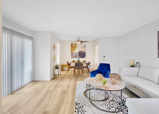 A living room with a white couch, a coffee table, and a dining table with chairs at Verandas Apartments, California, 91791