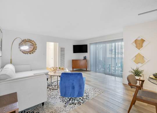 A living room with a white sofa, a blue chair, and a wooden cabinet at Verandas Apartments, California, 91791