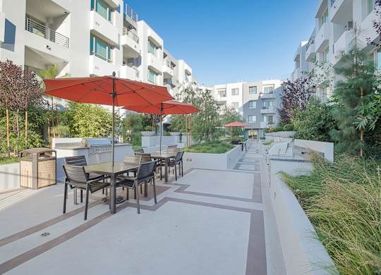 A patio with a table and chairs under a red umbrella at Woodley Sara Apartment, Van Nuys