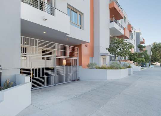 A modern building with a white and orange facade and a metal fence at Woodley Sara Apartment, California, 91406