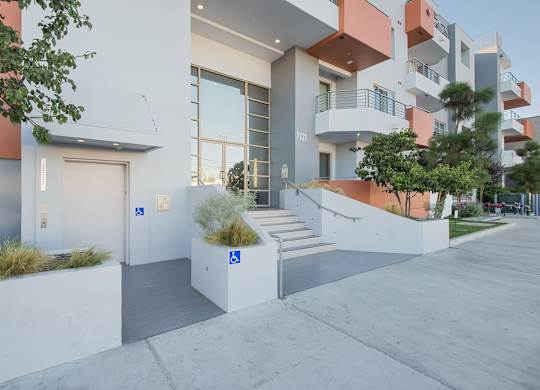 A modern building with a white and orange exterior and a tree in front at Woodley Sara Apartment, Van Nuys, 91406