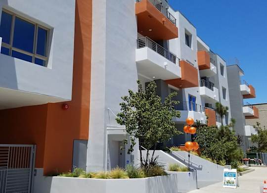 A modern apartment building with orange and white balconies at Woodley Sara Apartment, Van Nuys