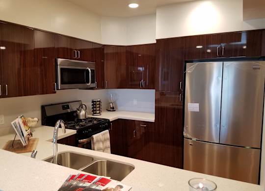 A modern kitchen with dark wood cabinets and stainless steel appliances at Woodley Sara Apartment, Van Nuys, 91406