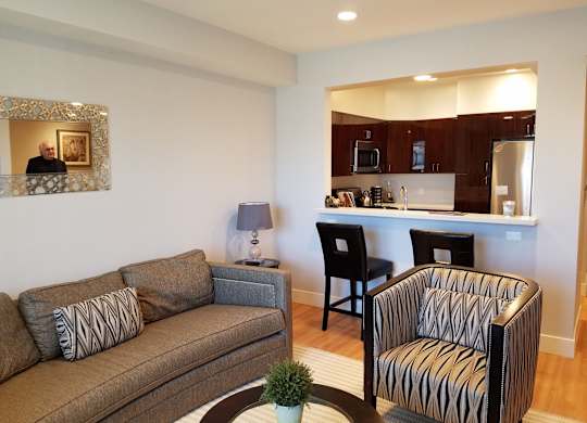 A living room with a brown couch, a striped chair, and a coffee table at Woodley Sara Apartment, Van Nuys, California