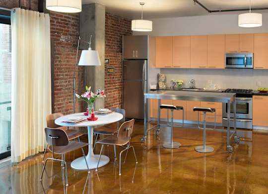 A kitchen with a table and chairs in front of a brick wall.