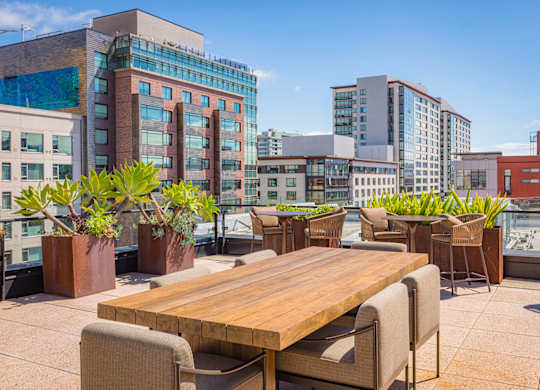A wooden table surrounded by chairs on a rooftop patio.
