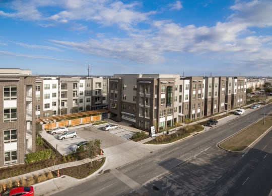 an aerial view of an apartment complex with a parking lot and a street at Arise Riverside, Texas