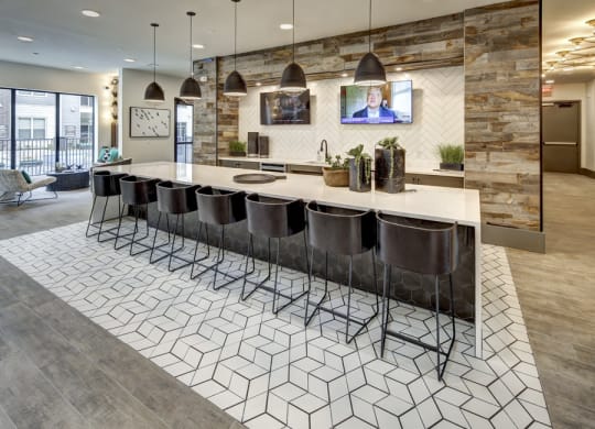 a kitchen with a large counter and chairs and a tv on the wall at Arise Riverside, Austin, TX 78741