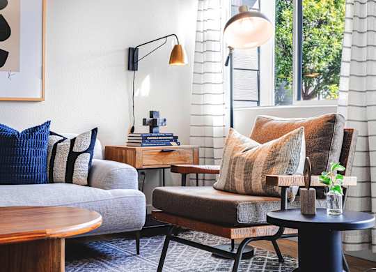 A living room with a grey couch, a brown chair, and a wooden table.