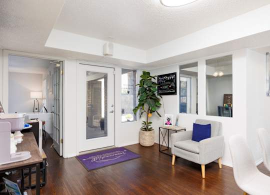 A living room with a white chair and a purple rug.