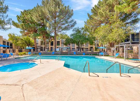 A large swimming pool surrounded by trees and chairs.