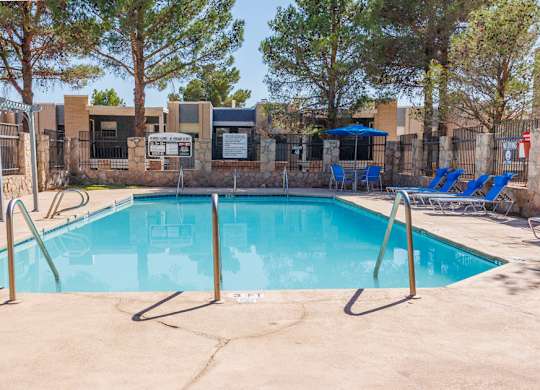 A pool surrounded by trees and a fence.
