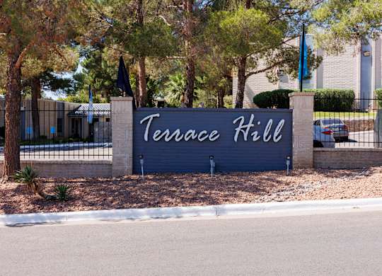 A sign that says Terrace Hill stands in front of a building.