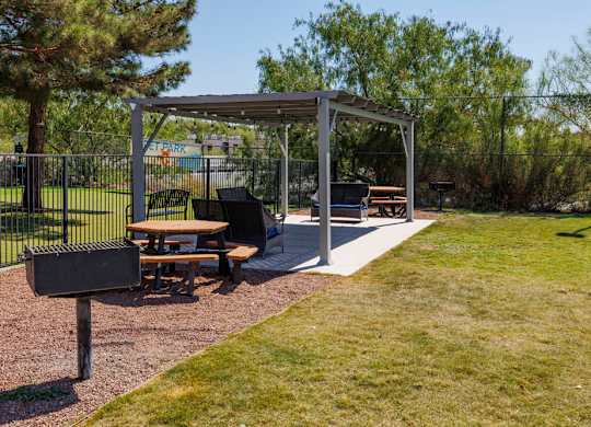 A picnic area with a grill and picnic tables.