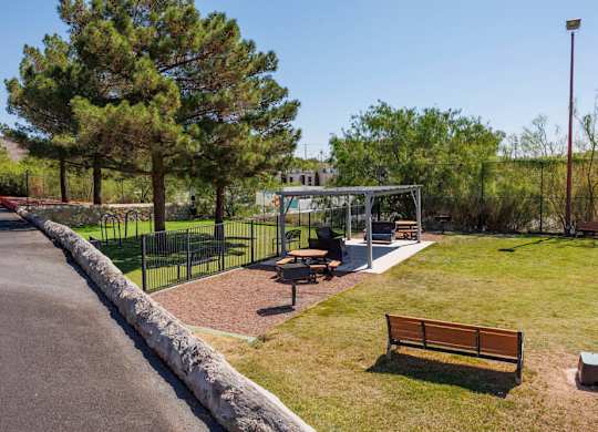 A park with a bench, a playground and a tree.