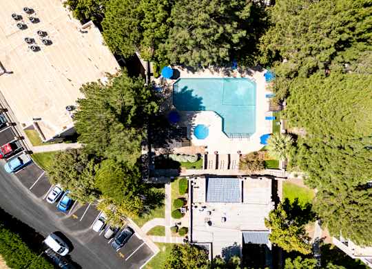 An aerial view of a parking lot with cars and a swimming pool.