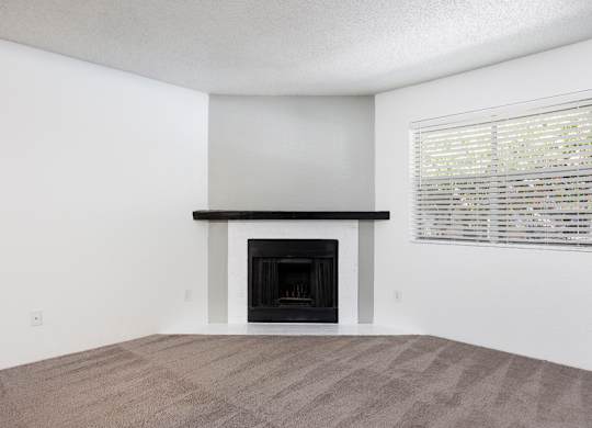 A room with a fireplace and a window with blinds.