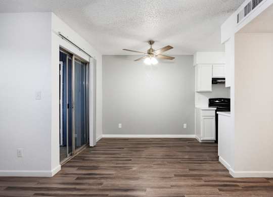 A room with a ceiling fan and a wooden floor.