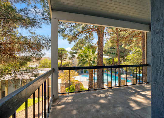 A balcony with a pool in the background.