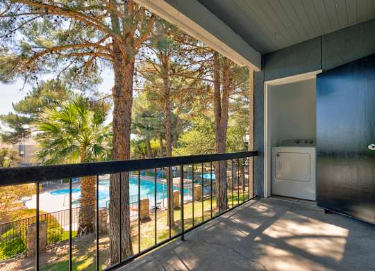A balcony with a pool and trees in the background.