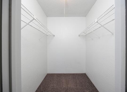 A walk-in closet with white walls and shelves.