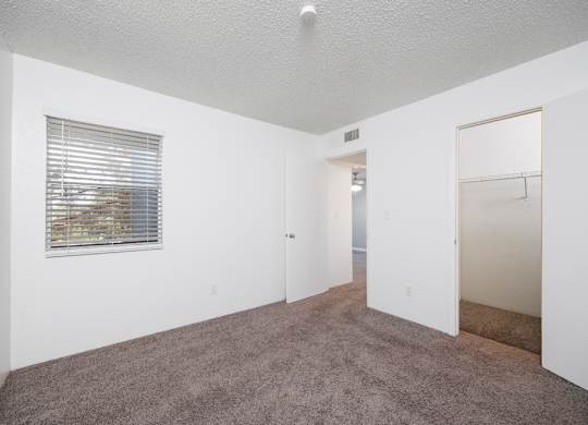 A room with a carpeted floor and a window with blinds.
