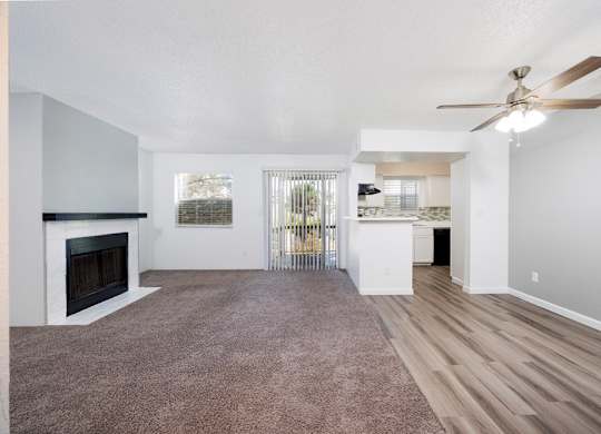 A spacious living room with a fireplace and a ceiling fan.
