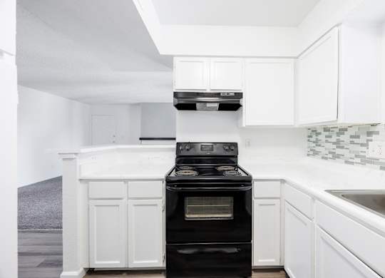 A black oven in a white kitchen.