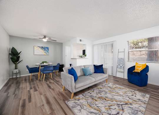 A living room with a grey couch, blue chairs, and a wooden floor.