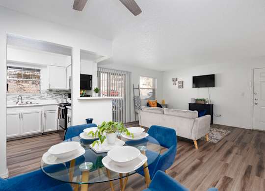 A modern living room with a glass table and blue chairs.