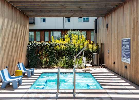 A small pool with a diving board and two chairs.