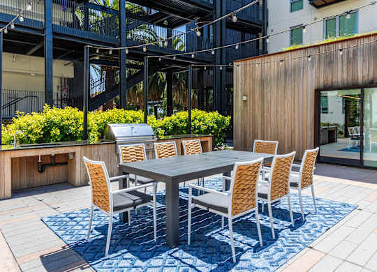 A table surrounded by chairs is on a patio.