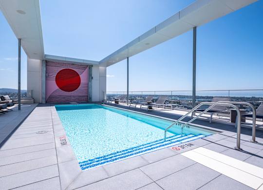 A swimming pool on a rooftop with a red circle on the wall.