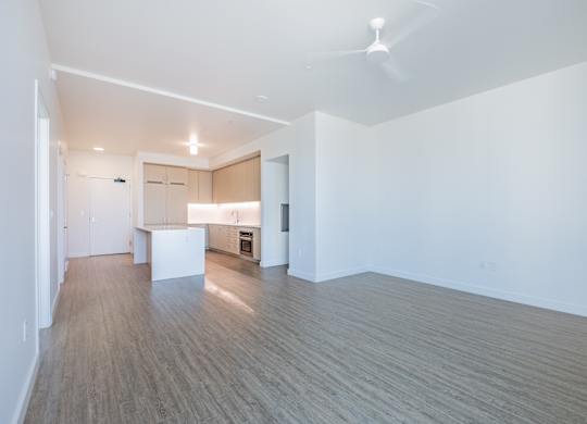 A room with a kitchen area and a dining table.