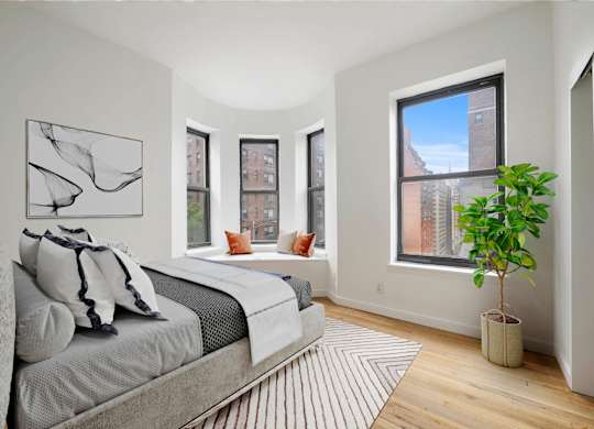 A bedroom with a large bed and a plant.