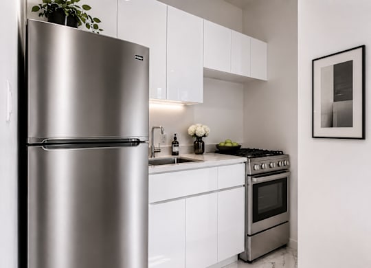 A modern kitchen with a stainless steel refrigerator and oven.
