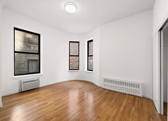 A room with wooden floors and two framed pictures on the wall.