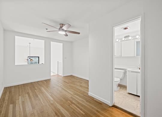 A room with a ceiling fan and a mirror on the wall.