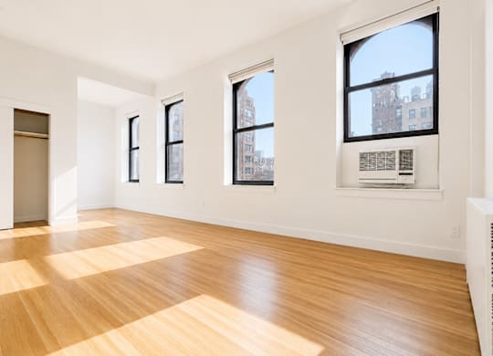 A room with wooden floors and three windows.