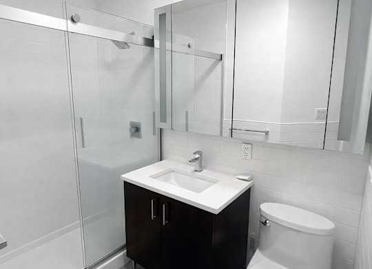 A white bathroom with a sink, toilet and shower.