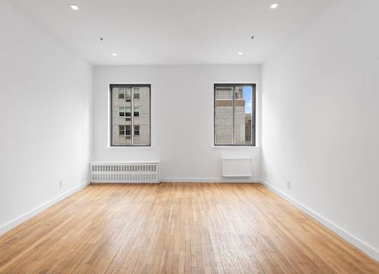 A room with wooden floors and two windows.