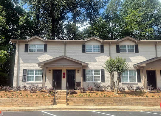 A two-story house with a red door and a small front yard at Waverly Manor Townhomes, Norcross, GA 30071
