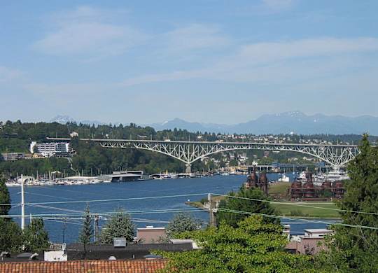 A bridge spans a large body of water with a mountain range in the distance.