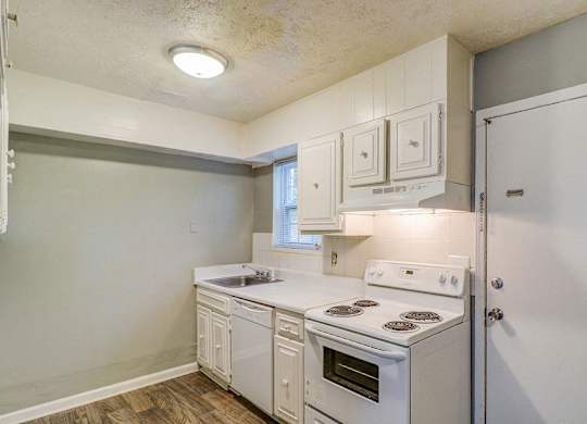 A kitchen with white appliances and cabinets.at Waverly Manor Townhomes, Norcross  