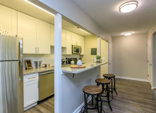 A kitchen with white cabinets and a refrigerator.