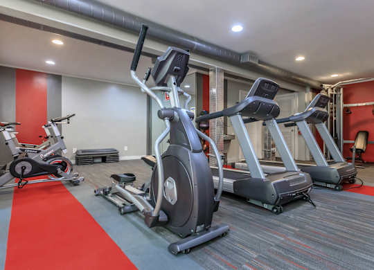 A gym with a red carpet and various exercise machines.