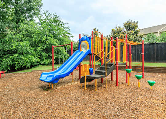 A playground with a blue slide and yellow and red play structures.